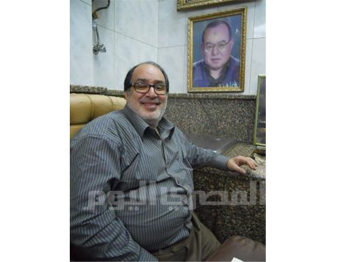 Mohammed Shaheen Sakr beside a photograph of his father.
